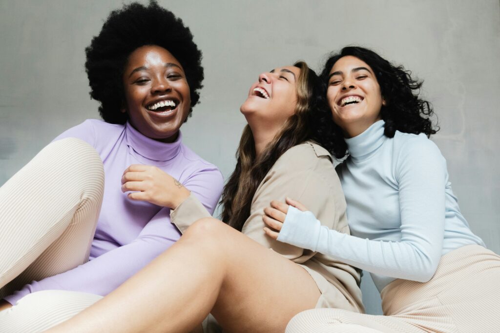 Three happy women laughing together highlighting Women in C-suite statistics