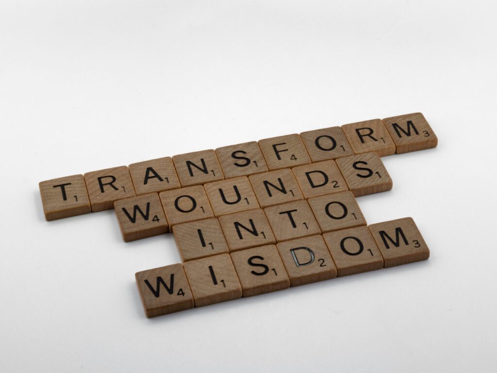 Scrabble tiles spelling empowering women quotes - "transform wounds into wisdom" represents uplifting female quotes about resilience