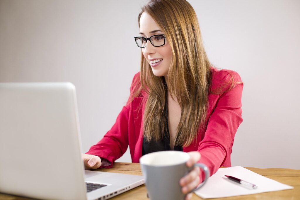 Executive woman in red blazer reviewing affordable women's leadership networks