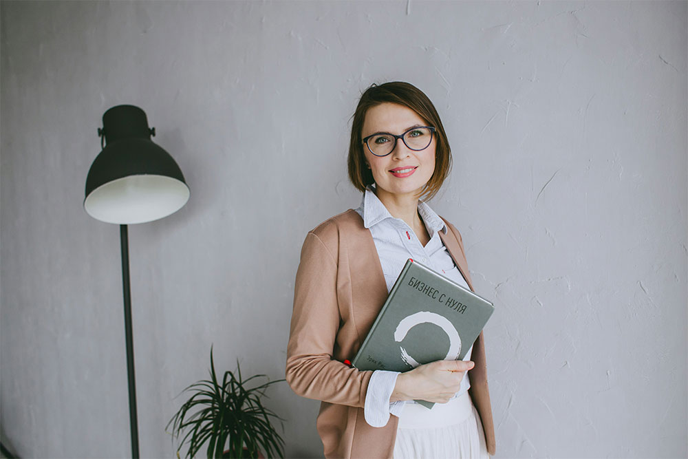 Entrepreneurial woman leader holding book while mentoring, showing entrepreneurship benefits to society through knowledge sharing and entrepreneurs driving innovation