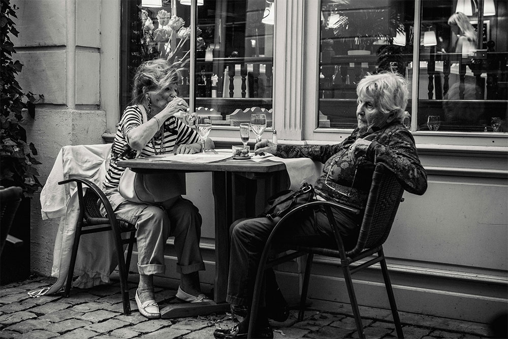 Two elderly women at a caf&eacute; discussing life goals and what is an accountability partner for long-term support.