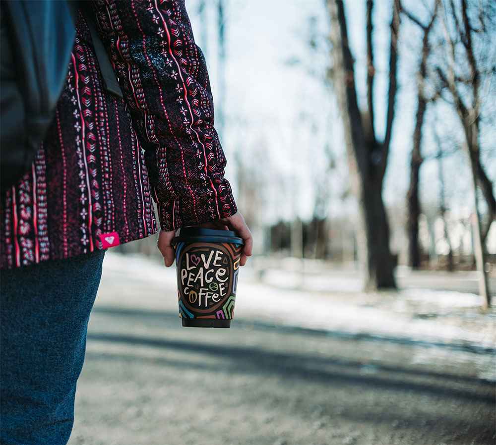 Woman entrepreneur with coffee cup representing social entrepreneurship impact through addressing underserved markets in coffee and community sectors