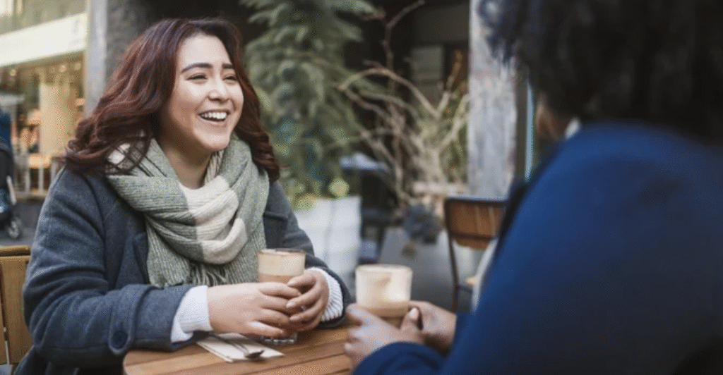 Women CEOs laughing over coffee drinks during female leadership development meeting