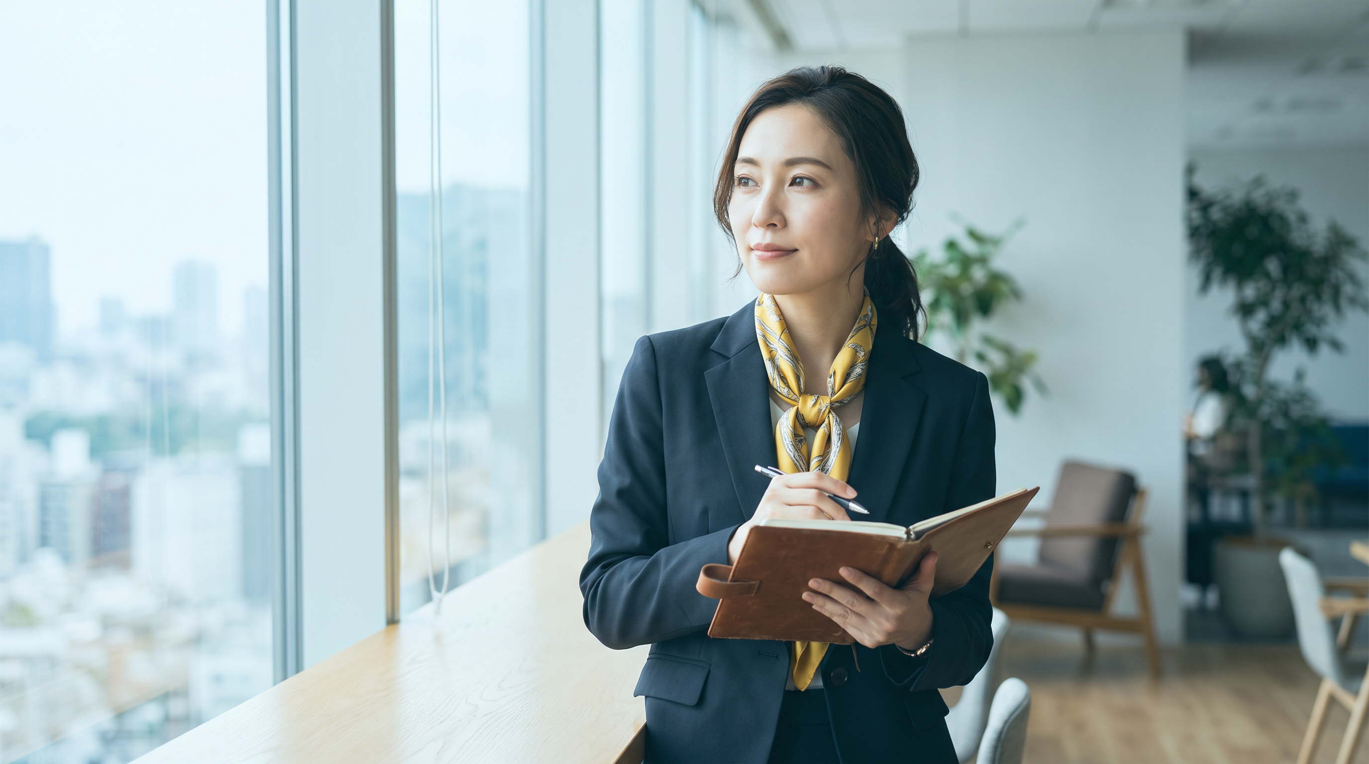 Confident woman executive by a window weighing an Ellevate Network membership